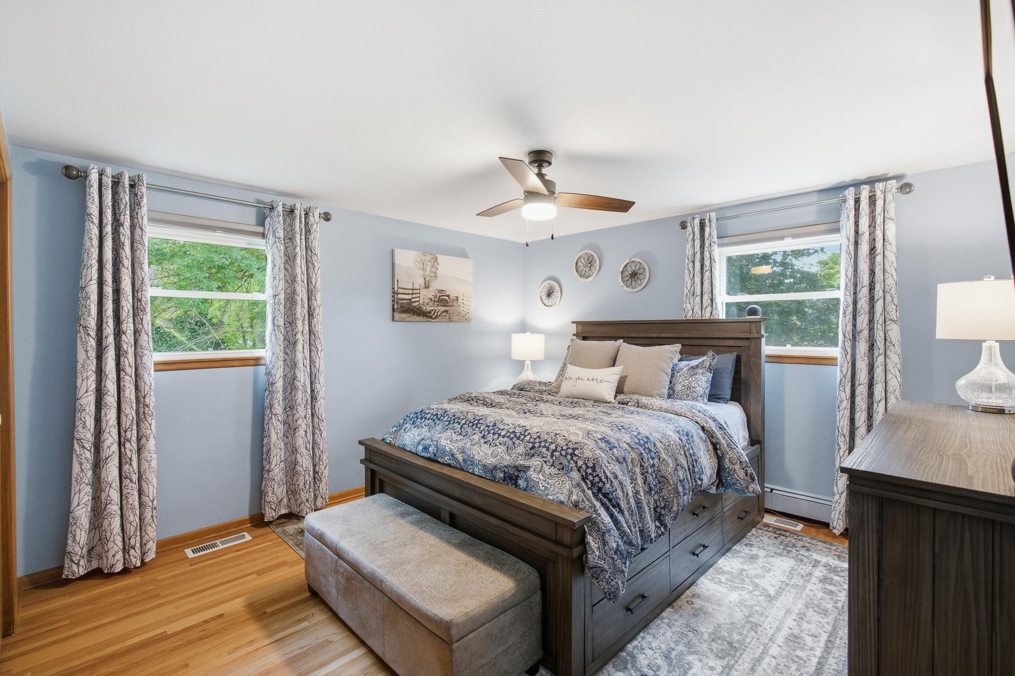 Spacious bedroom featuring beautiful hardwood floors, abundant natural light, and a warm, inviting atmosphere.