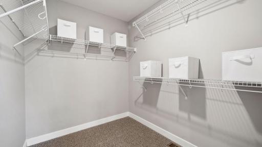 One of two walk-in closets in the primary suite. Photo of model home, colors and finishes may vary.