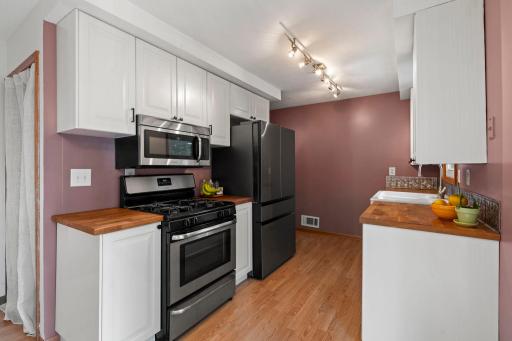 Bright kitchen with white cabinetry and butcher block countertops