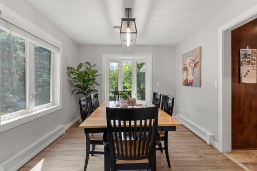 The bright dining area is framed by windows and illuminated by an updated light fixture, creating an inviting setting for meals and gatherings