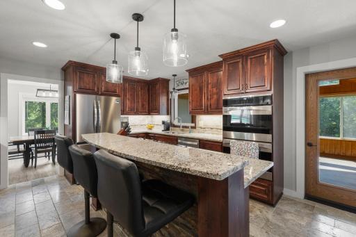 The beautiful kitchen features stainless appliances, island seating, double over and access to the sunroom
