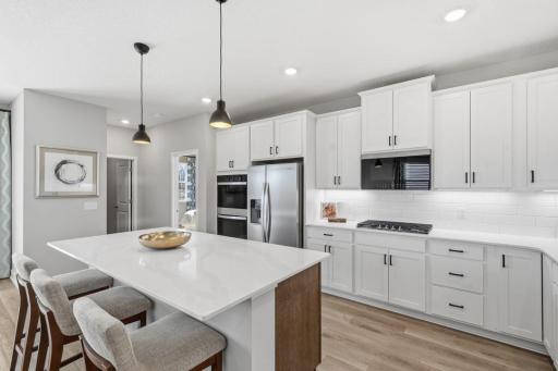 In this view you can see the door to the primary bedroom and the laundry room at the far end of the kitchen. Photo of the model home. Kitchen package will be different.