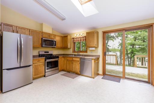 Large eat-in kitchen featuring newer stainless appliances and a skylight above.