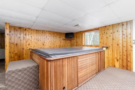 Large corner hot tub with exhaust fan above and tv shelf.