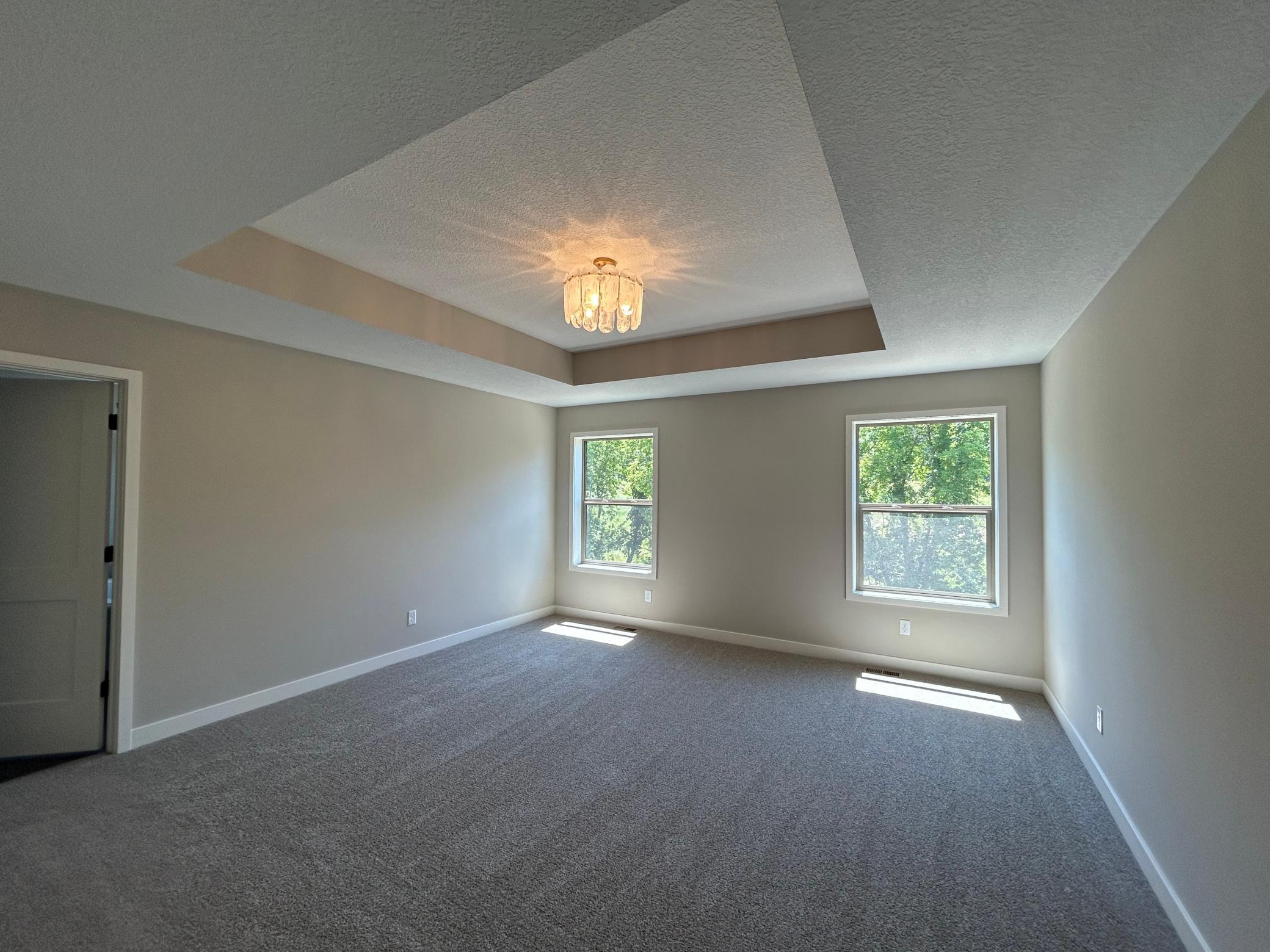 Primary suite with tray vault ceiling and beautiful light fixture