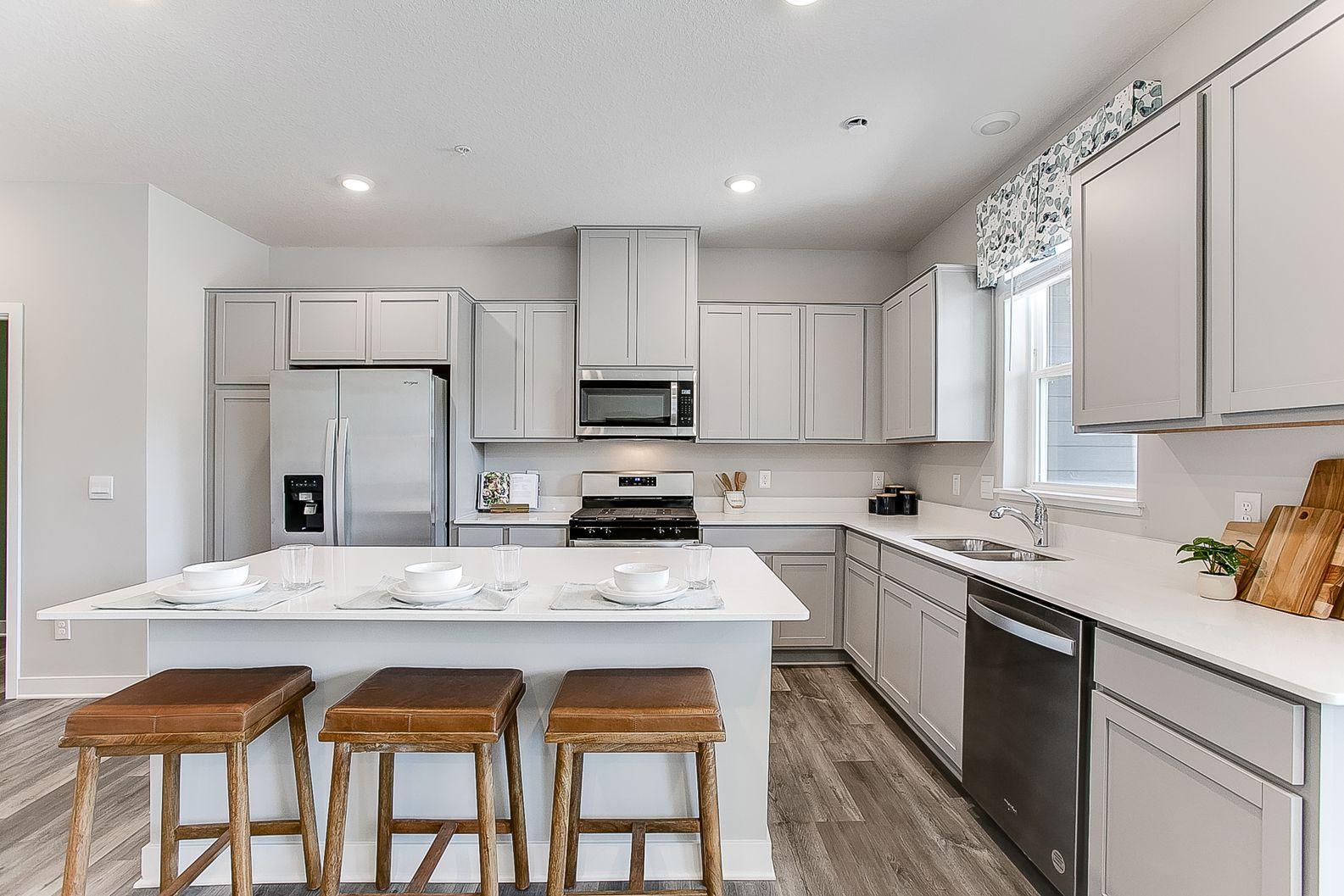 A kitchen built to both perform and enjoy - complete with a stainless appliance package, loads of cabinet space, quartz countertops, and an oversized center island. Model photos. Options and colors will vary.