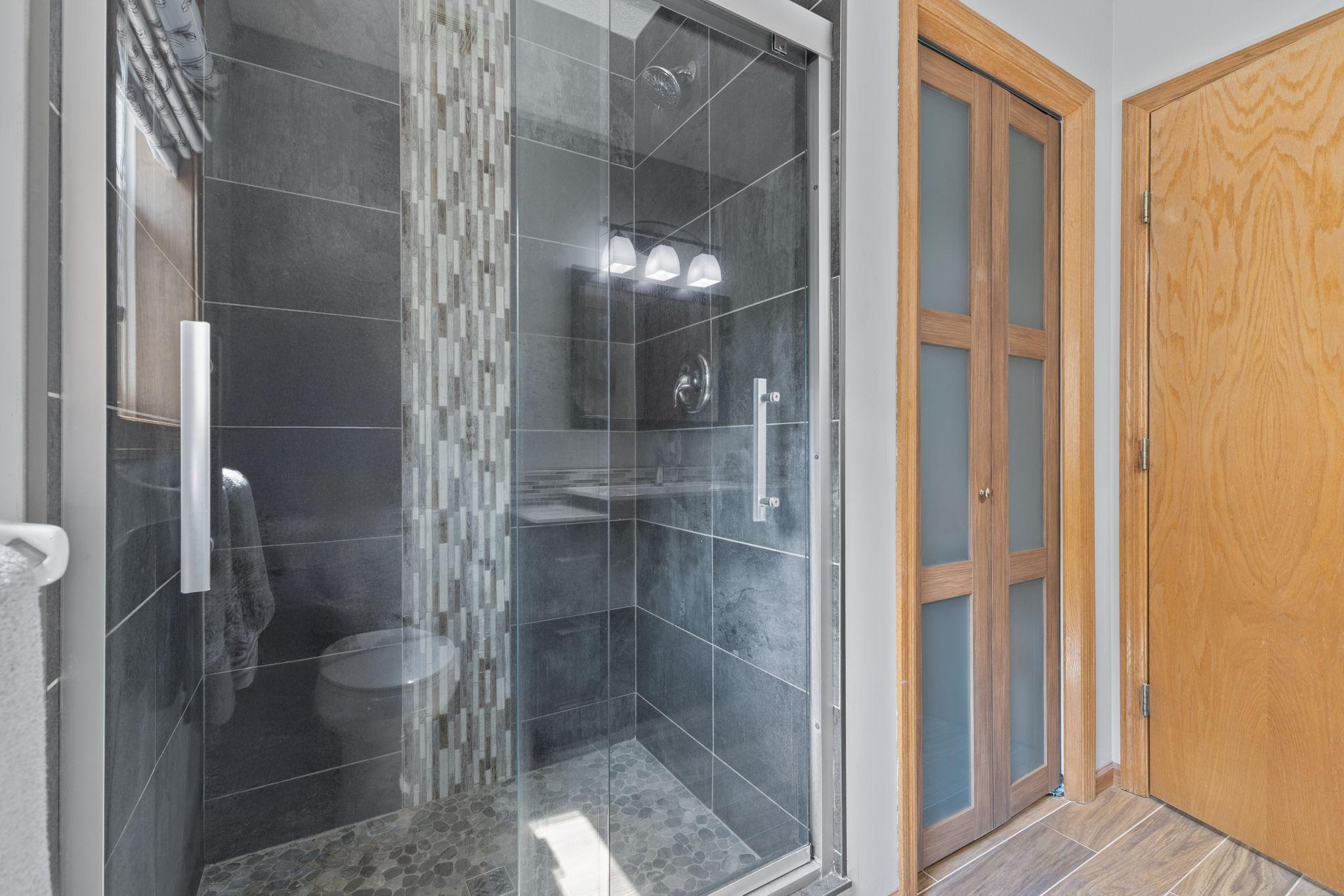 Beautiful shower with glass doors and tile surround.