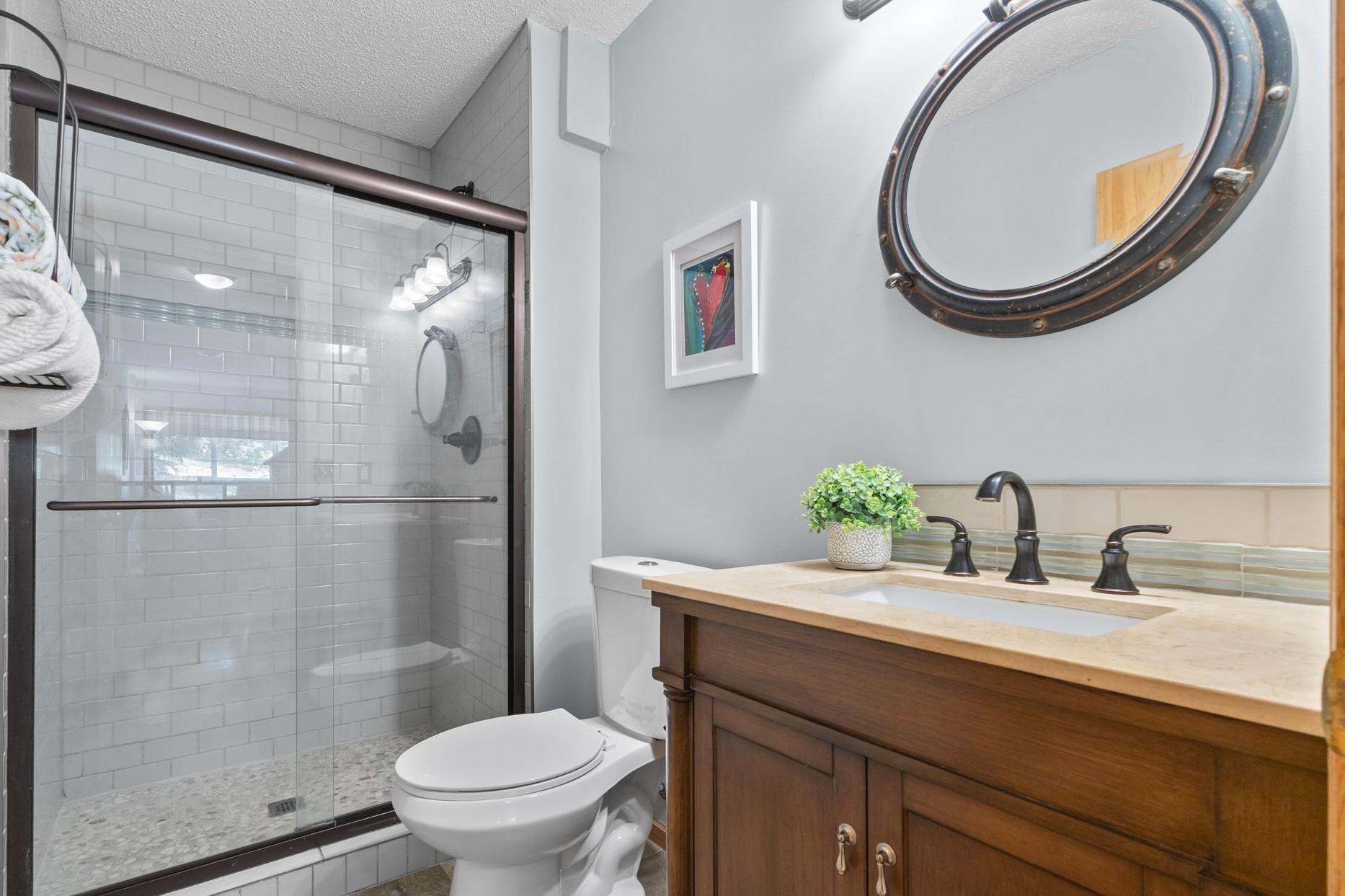 The lower level 3/4 bathroom features upgraded flooring, shower doors and cabinetry.
