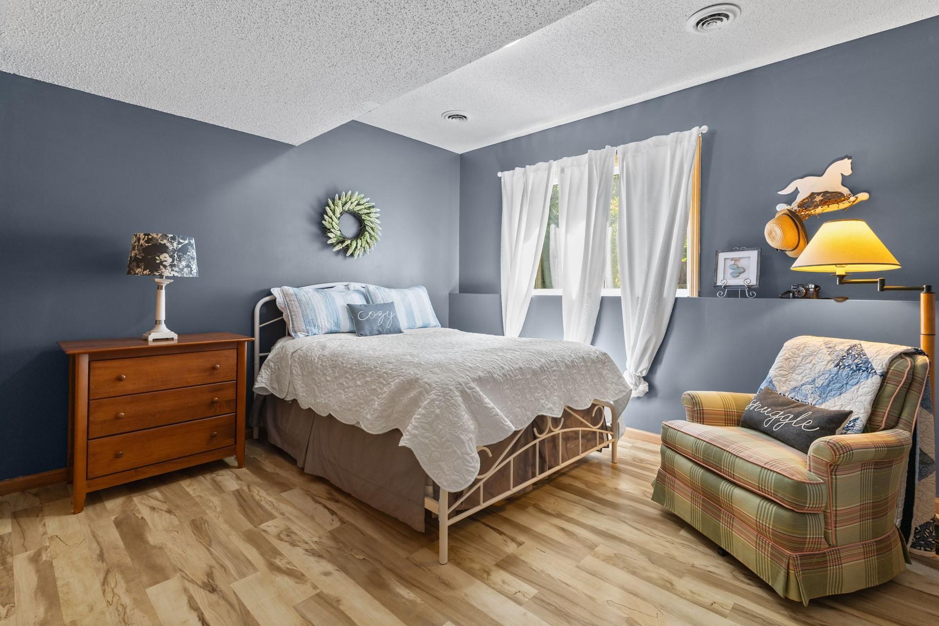 This cozy lower level bedroom features an electric fireplace (included), and peaceful views of the back yard.
