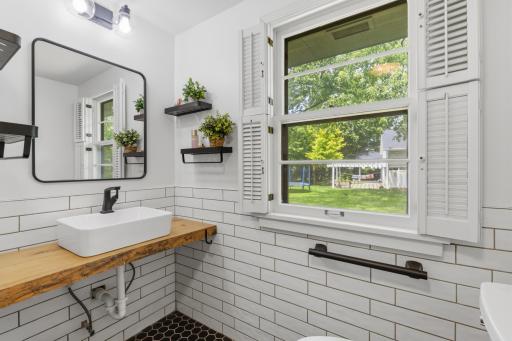 Unique solid wood vanity top with a vessel sink. Subway tile wainscoting and mosaic tile flooring