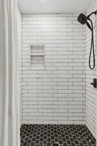 Custom walk-in shower features curbless entry, shampoo niche and subway tile surround