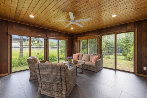 Porch features wood paneled walls and ceiling with fan