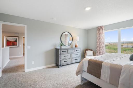 Primary bedroom has large windows and private full bathroom. Model photo. Options and colors may vary.
