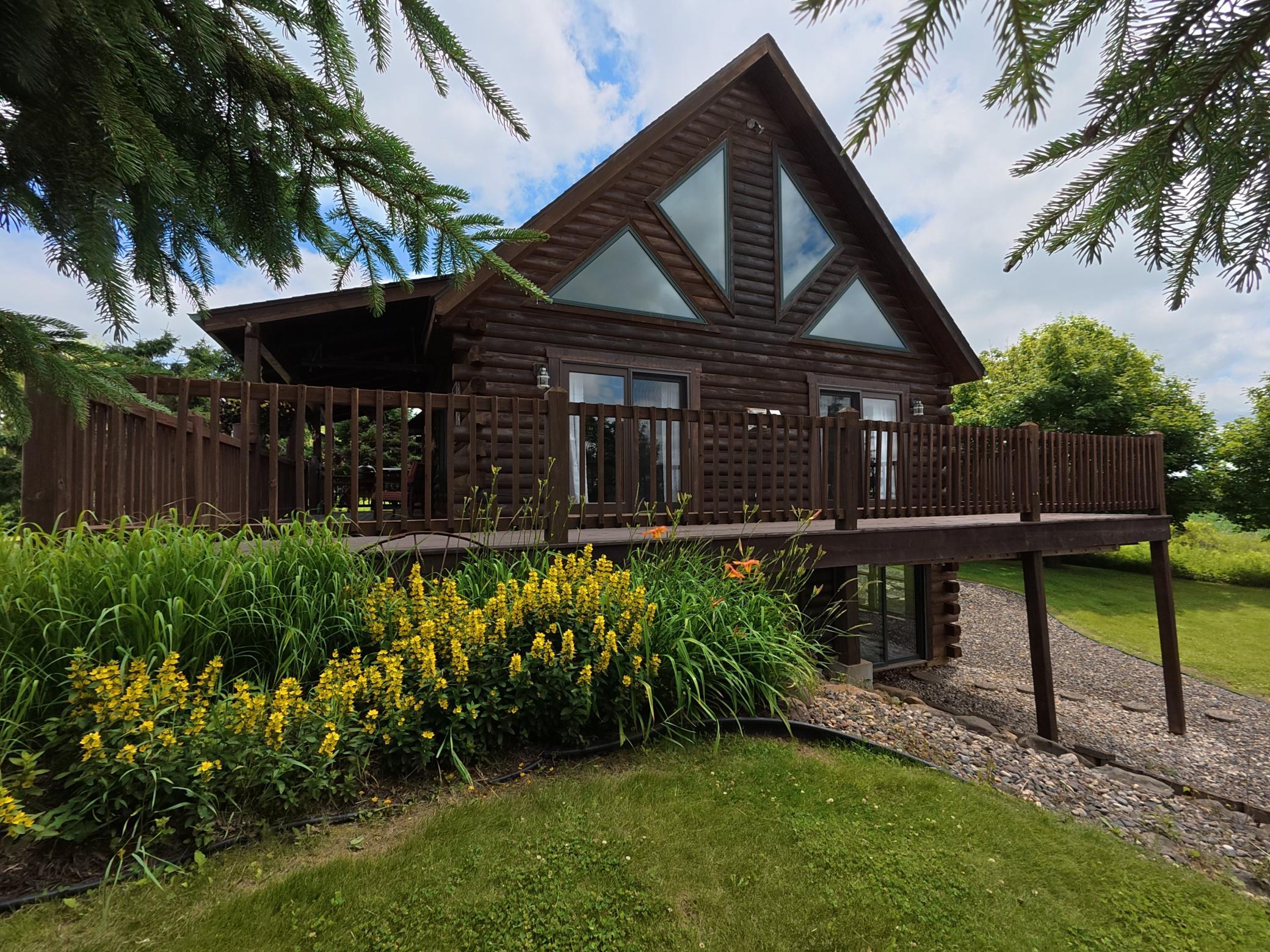 Side profile highlights the wrap-around porch and walkout basement. Expansive windows flood the interior with natural light and scenic views.