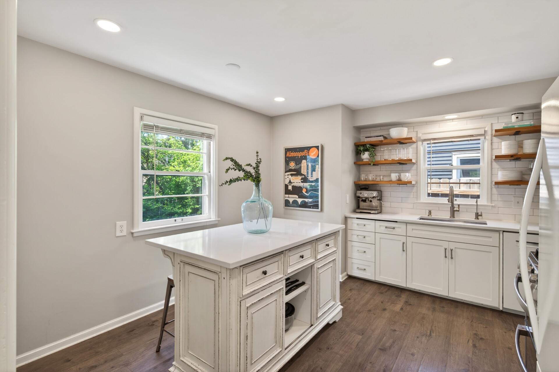 Updated Eat-In Kitchen fit with its own island, quartz countertops, undermount sink, tile backsplash, floating shelves, and newer appliances
