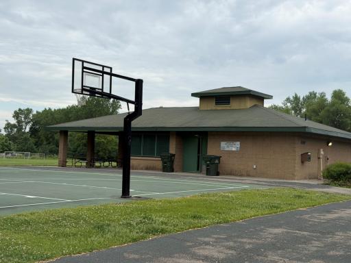 This photo highlights one section of the park, featuring bathrooms, basketball courts, a playground, and other amenities