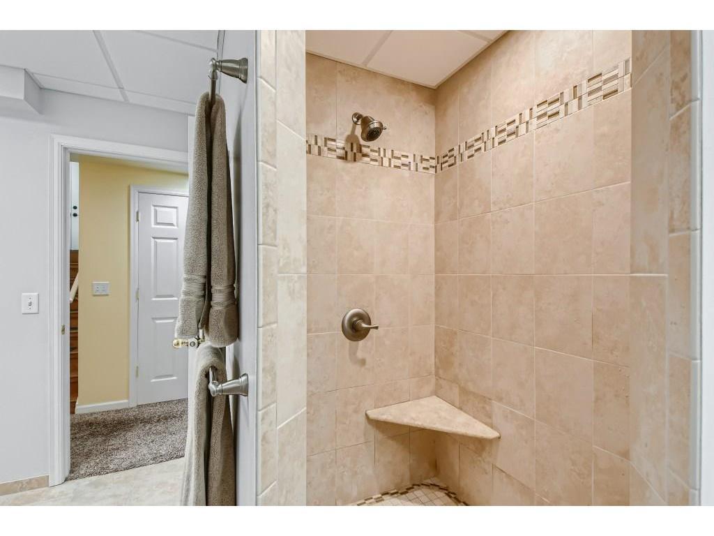 The lower-level bath features a beautiful walk-in tile shower with custom accent borders and a built-in corner bench!