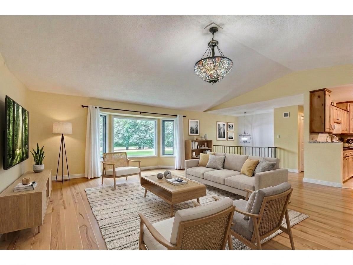 Bright, open living room with vaulted ceilings, beautiful hardwood floors, and a large bay window. Flows effortlessly into the dining and kitchen areas! *Virtually staged to show design options.