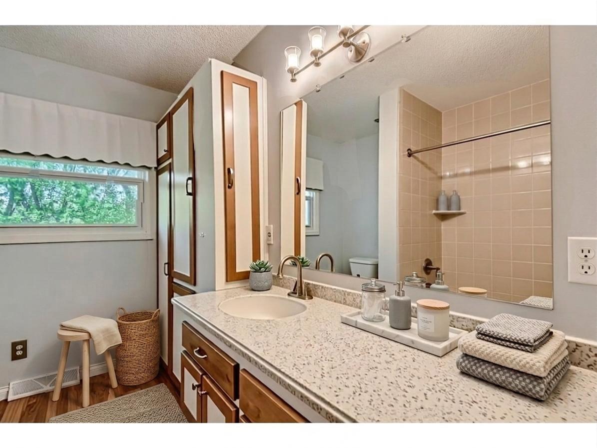 The full upper-level bathroom features an expansive quartz-look vanity, built-in linen storage tower, bright vanity lighting, and a window for natural light! *Virtually staged to show design options.