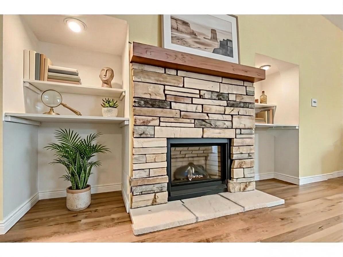 Cozy gas fireplace in the upper-level family room, featuring classic stone facing, a thick wood mantel, and custom built-in shelving! *Virtually staged to show design options.