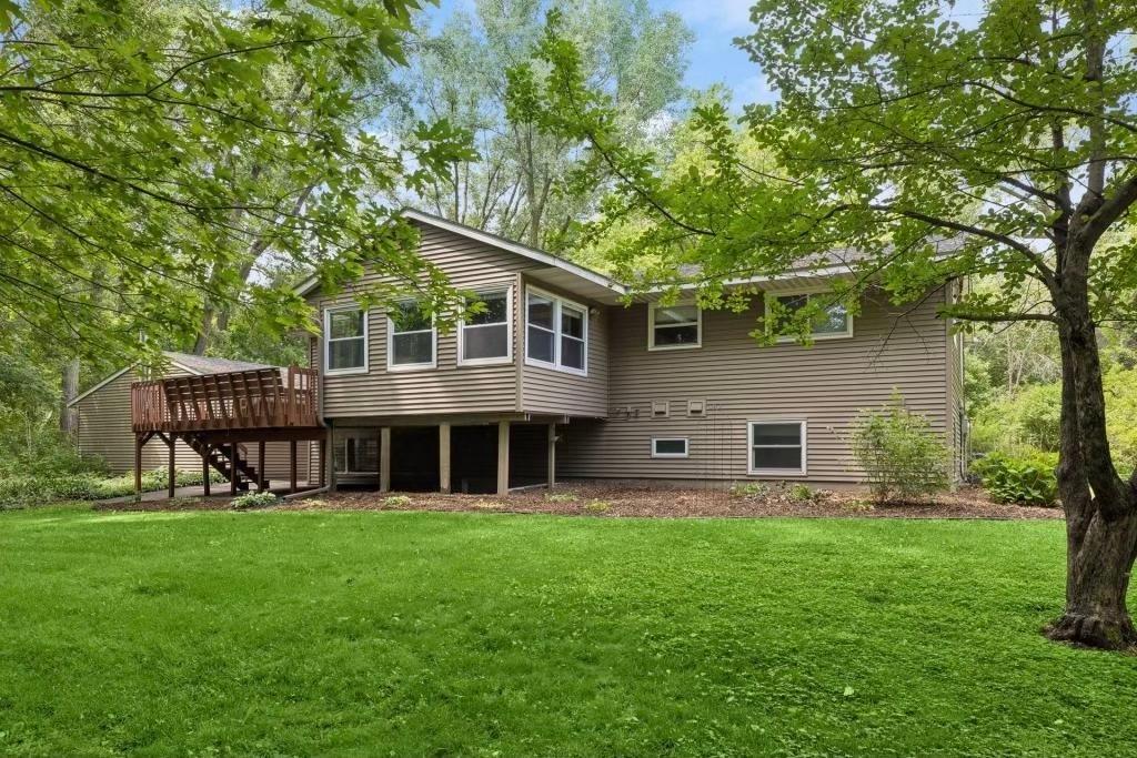 Another view of the home's exterior showing the spacious backyard, mature trees, and the elevated back deck perfect for outdoor living!