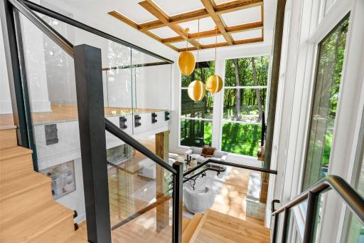 Architecturally striking stairway with glass railing detail connecting the main living area to the upper bedrooms