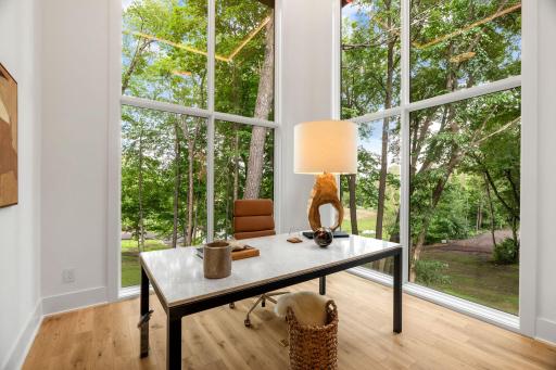 Stunning main floor office off the entryway with floor to ceiling windows, soaring ceilings, and flooding with natural light