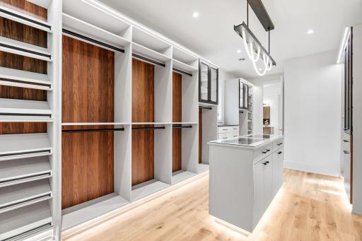Luxurious custom walk-in closet featuring illuminated display cabinetry, a center storage island, built-in organization systems, and designer lighting