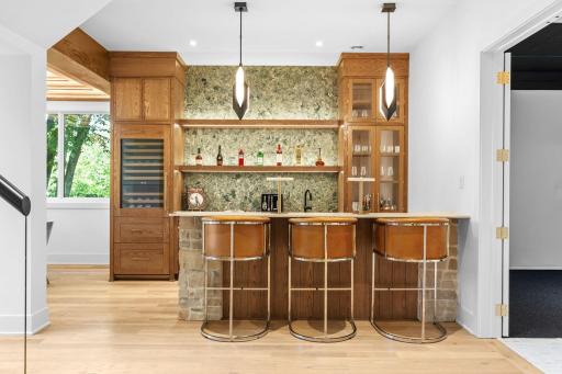 Stunning wet bar with white oak cabinets, beverage fridge, barstool seating, and fabulous Cambria countertops