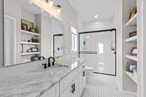 Beautifully designed Primary bathroom with Granite countertops, tiled flooring and gorgeous floating shelves.