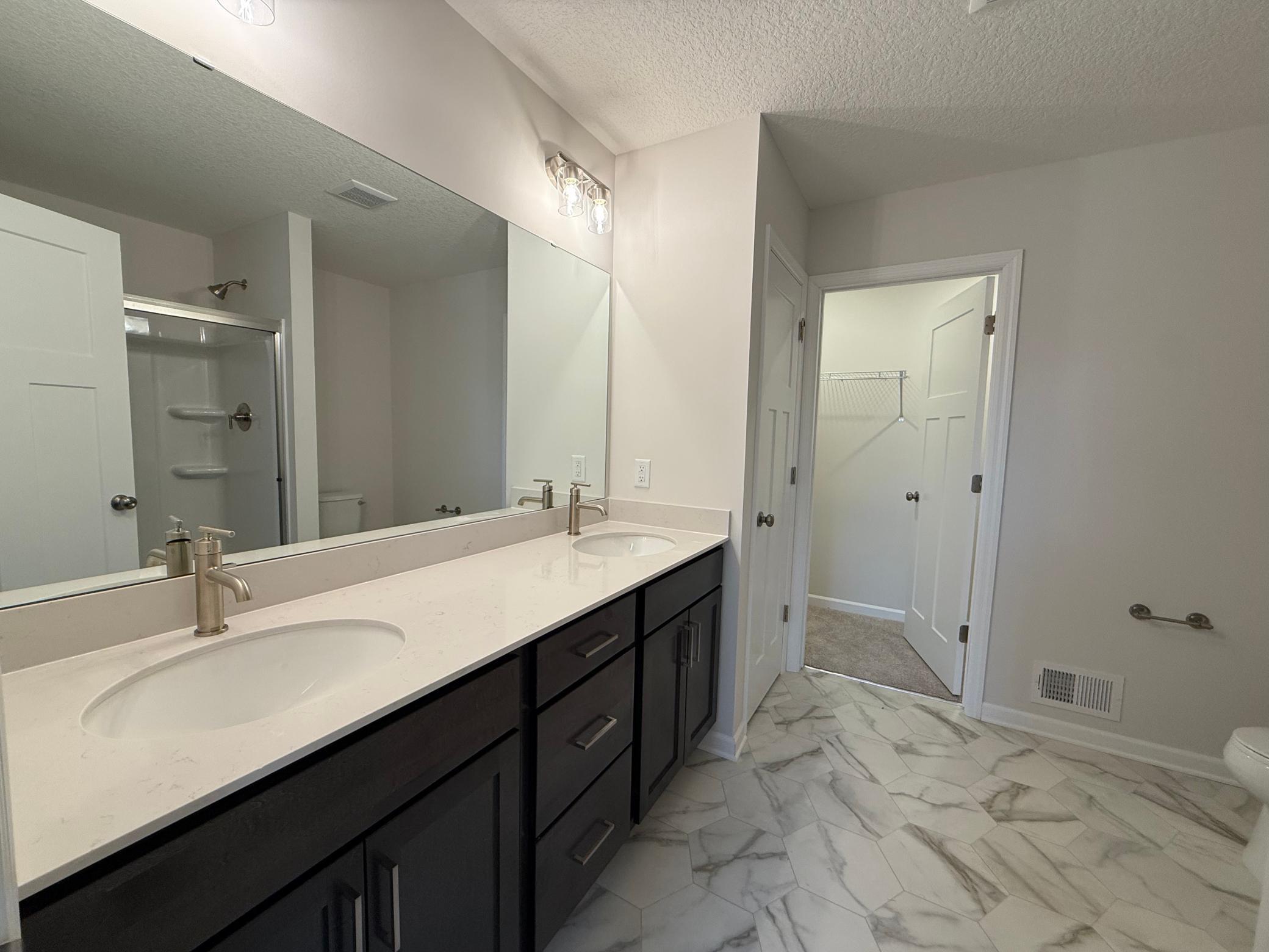 Dual vanity in the private en-suite bath provides maximum functionality. Features a large shower.