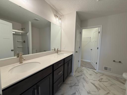 Dual vanity in the private en-suite bath provides maximum functionality. Features a large shower.