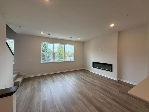 This spacious living room has excellent scenery featuring large windows, a fireplace, and enough space for even the biggest couches.