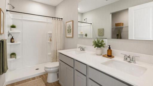 The lovely en-suite bathroom for the primary bedroom includes double sinks on an oversized vanity with a beautiful quartz countertop. Photo of a model home, colors and finishes vary.