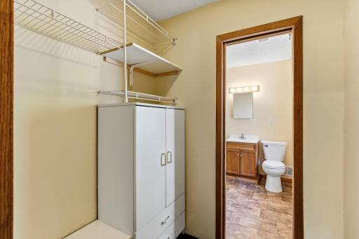 Walk-in closet with built-in shelving and convenient access to the primary bathroom.