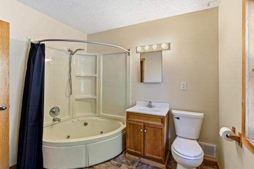 Primary bathroom featuring a corner jetted tub, vanity, and easy-care flooring.