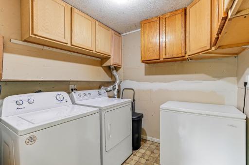 Dedicated laundry room featuring upper storage cabinets and additional space for organization.