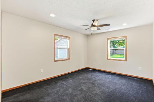 Bright primary bedroom with recessed lighting, ceiling fan, and large windows overlooking the backyard.