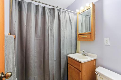 Convenient full bathroom featuring a shower/tub combo, ample lighting, and vanity storage.