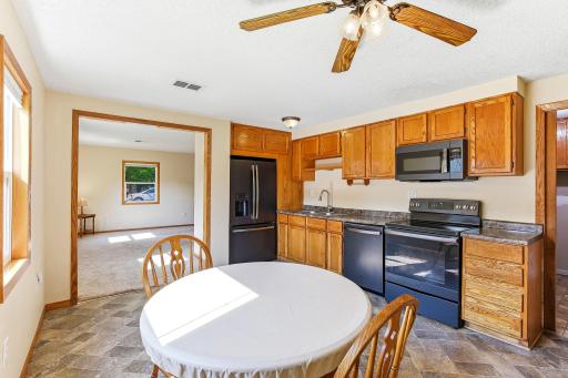 Eat-in kitchen featuring abundant oak cabinetry, black appliances, and a spacious dining area.