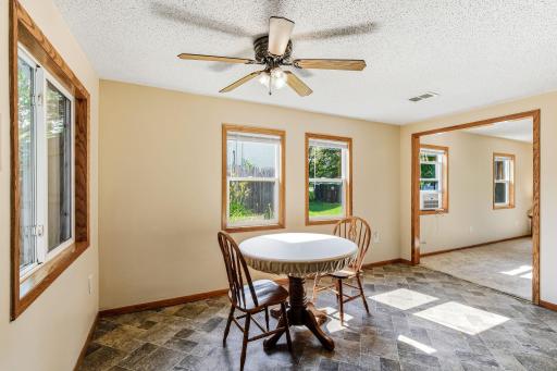 Sunny dining area with large windows, ceiling fan, and an open connection to the living room.