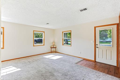 Bright, spacious living room filled with natural light from multiple windows, with a welcoming front entry.