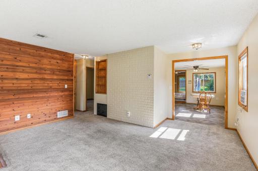 View from the living room showcasing warm wood accents, a decorative brick feature wall, and easy access to the dining space.