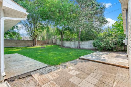 Private backyard oasis with a fully fenced yard, multiple outdoor seating areas, and mature shade trees.