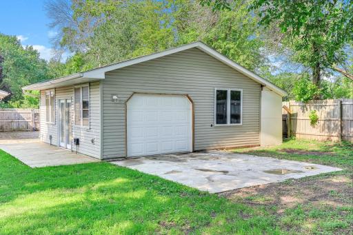 Rear view of the insulated detached garage featuring a back overhead garage door, deck, and ample outdoor space.
