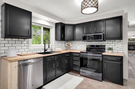 The freshly updated kitchen offers new butcher block counters, tile backsplash, enameled cabinets and an amazing oversized sink with a new faucet.