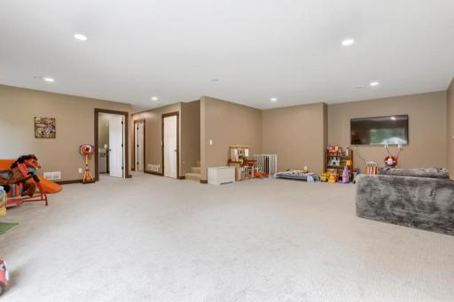 Lower level family room with Bedroom #5 to the left. New carpet and fresh paint on all levels in 2025.