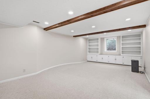 Lower-level family room with decorative wood beams and additional built-in cabinets