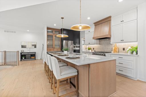 The heart of the home is the stunning kitchen, featuring a large center island, quartz countertops and tile backsplash.