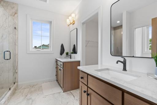 The private 3/4 bath showcases a beautifully tiled walk-in shower, dual vanities, and elegant finishes that create a spa-like retreat.